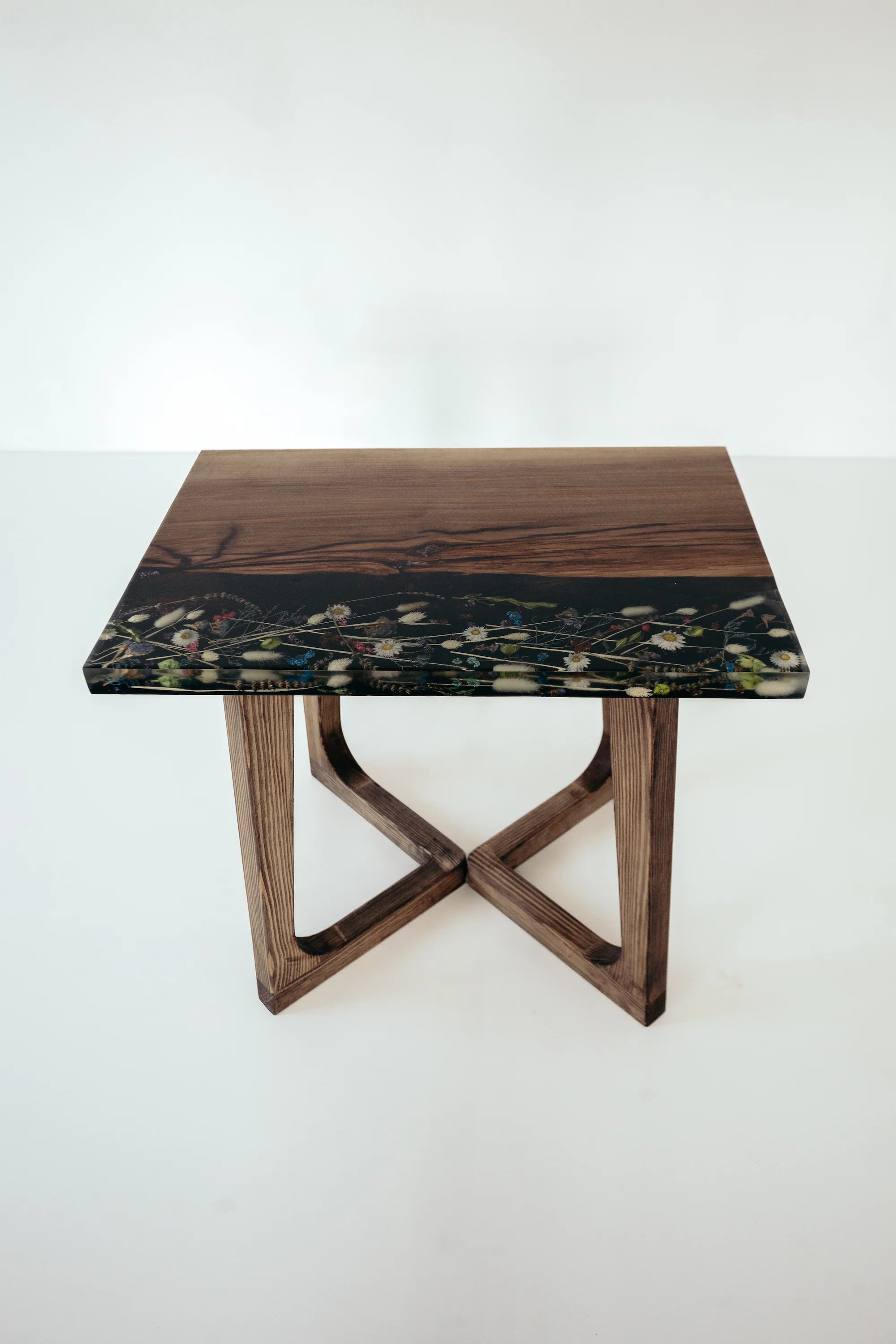 Square table with a dark green marble top and wooden base on a white background